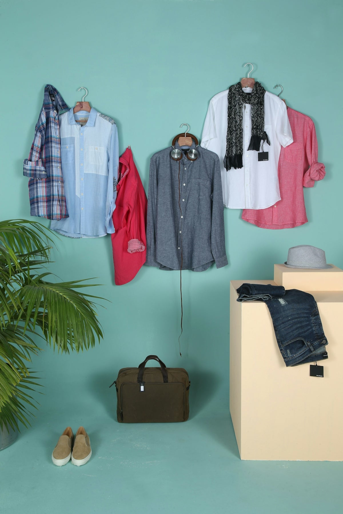 Clothing and accessories are stylishly arranged against a wall.