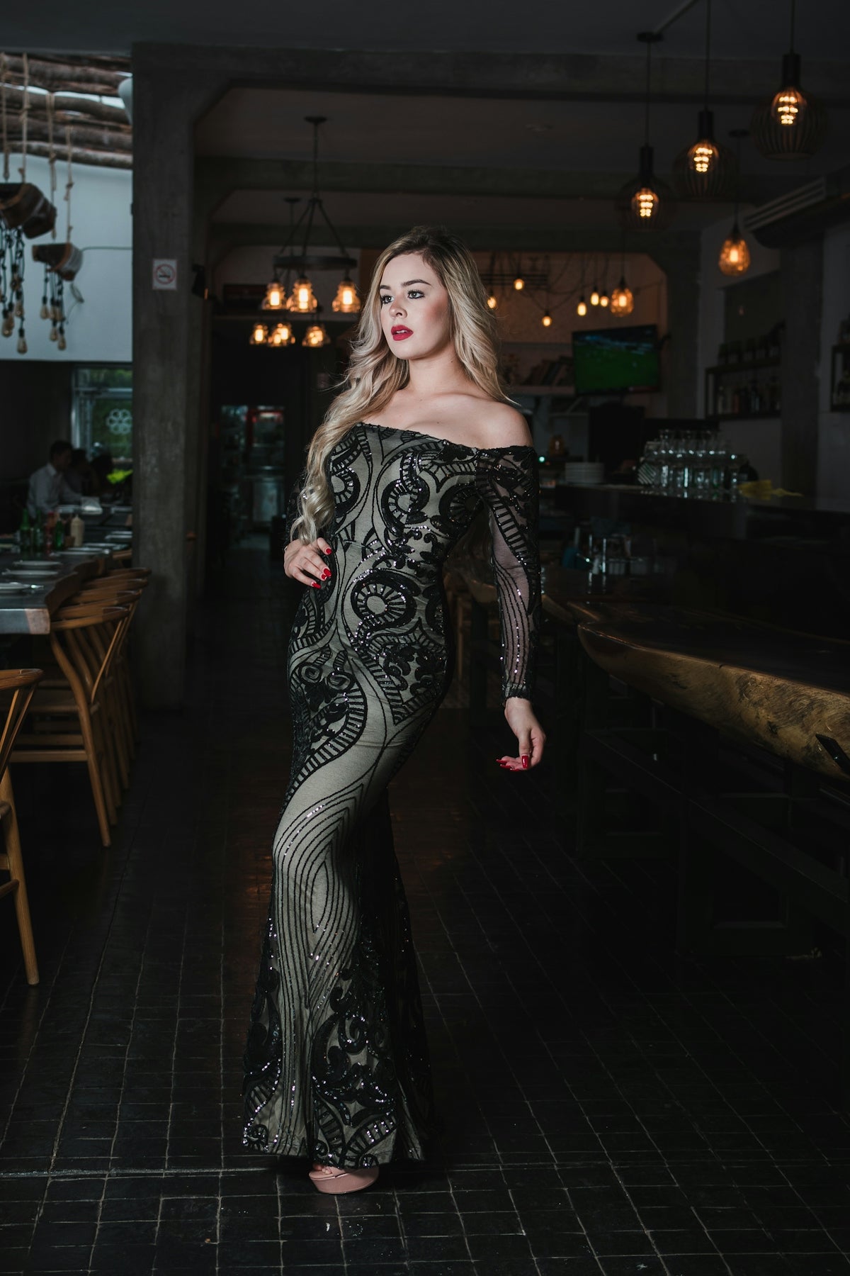 Woman in elegant sequined dress poses indoors.