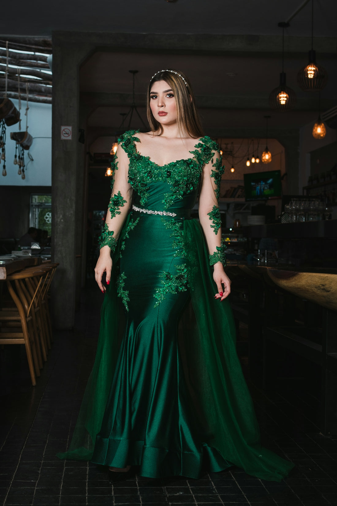 Woman in elegant green lace gown with long sleeves