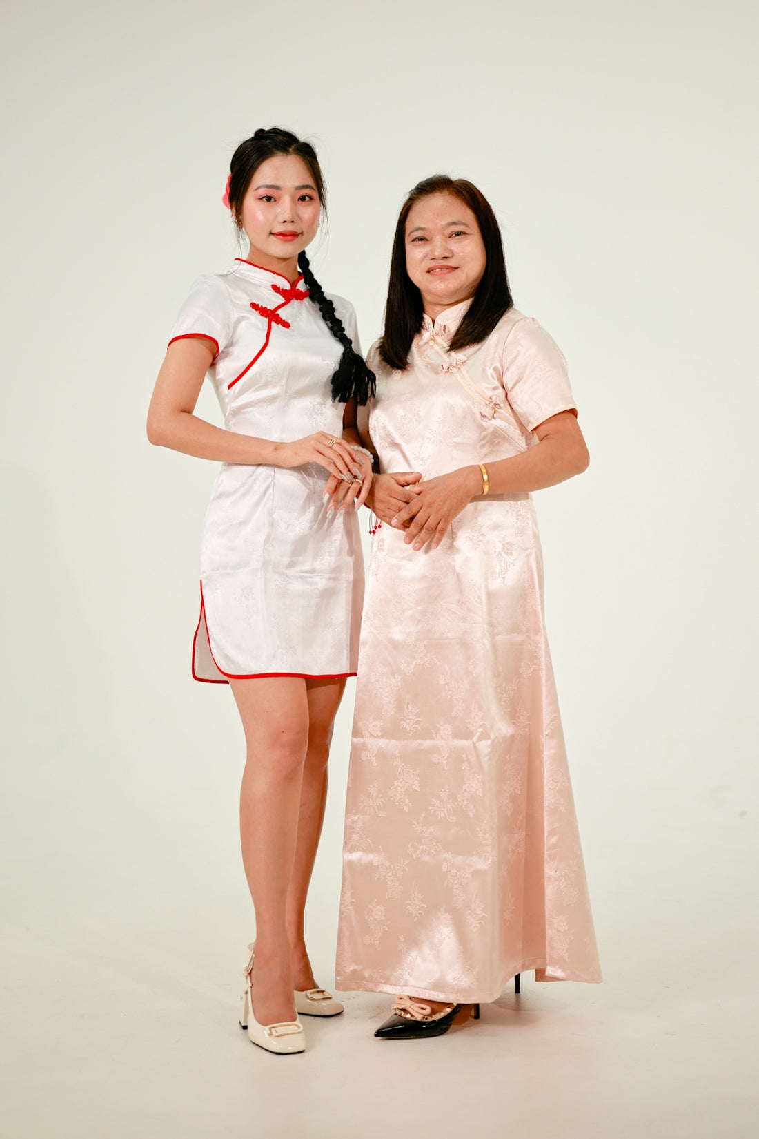 Two women in traditional chinese dresses stand together.