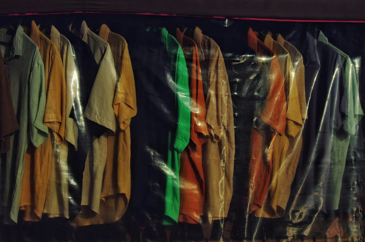 Various clothes hanging on a rack behind plastic