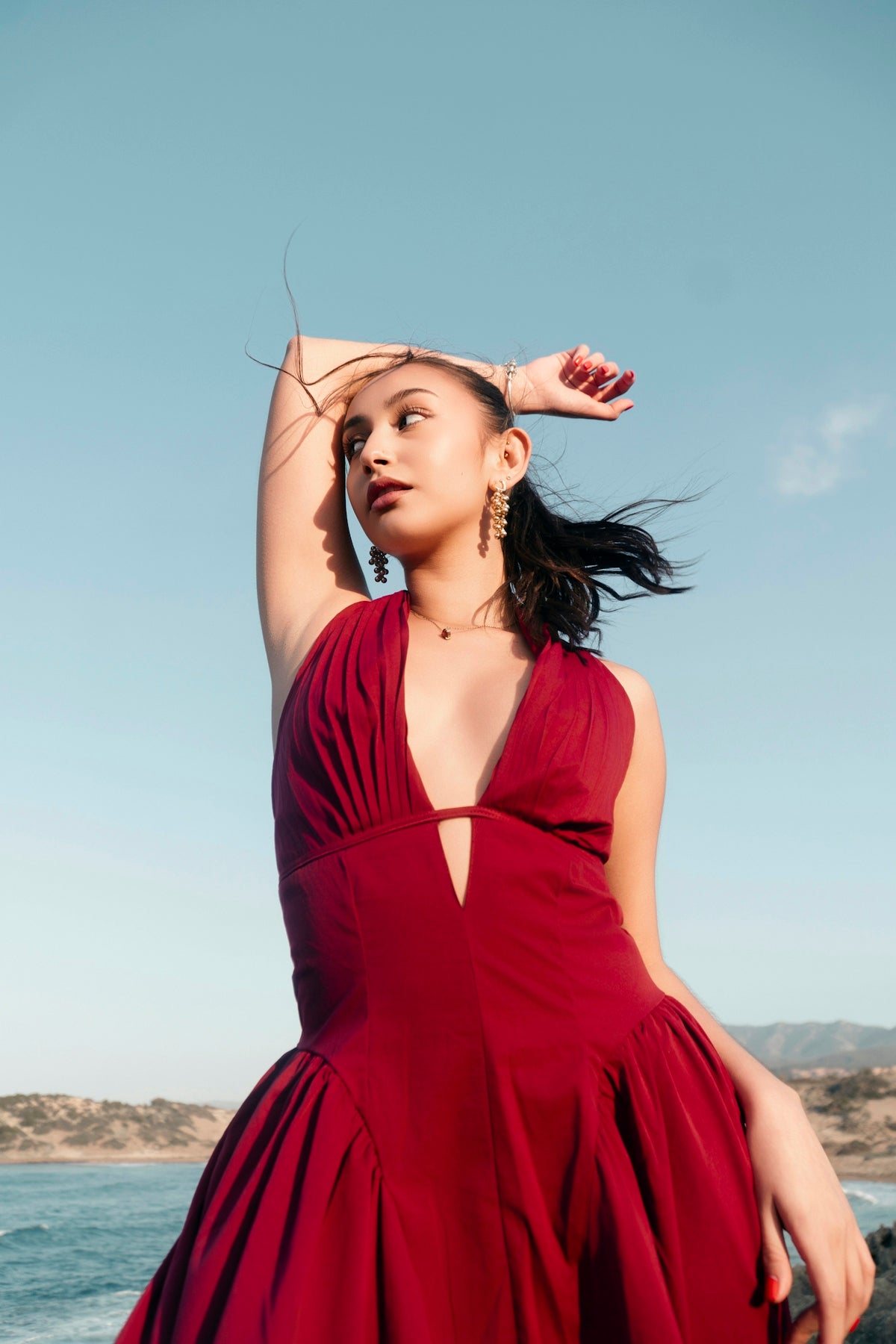 Elegant woman in red dress by the coast